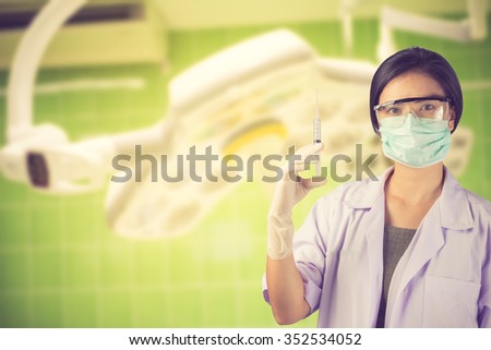 Woman Doctor holding syringe on surgical room  background vintage color