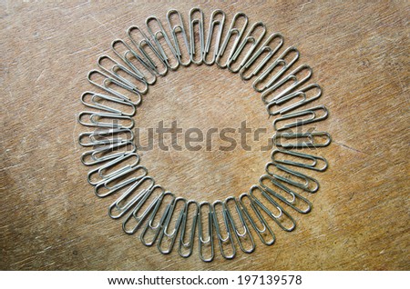 Paper clips as circle frame in wood background