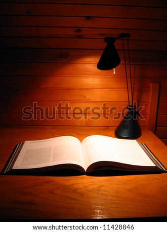 Open book on table alight whit desk lamp