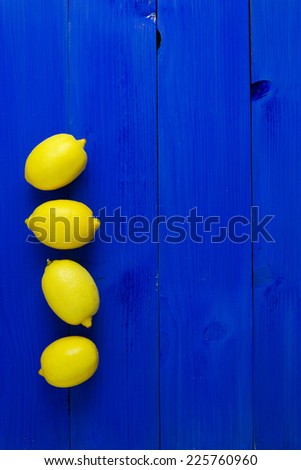 Four lemons over blue wooden background with copy space (negative space)