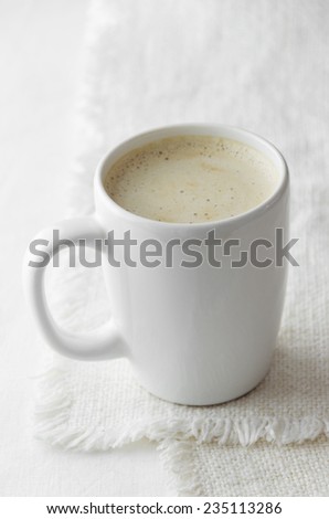 Cappuccino in a white mug over white cloth