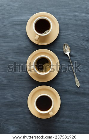 Coffee cups and a spoon over chalk textured table, above view