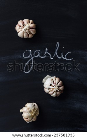 Cloves of garlic over black chalkboard with handwritten word \