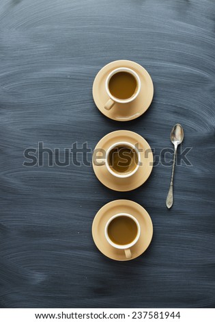 Coffee cups  and a spoon over chalk textured table, above view