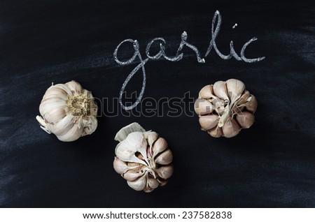 Cloves of garlic over black chalkboard with handwritten word \