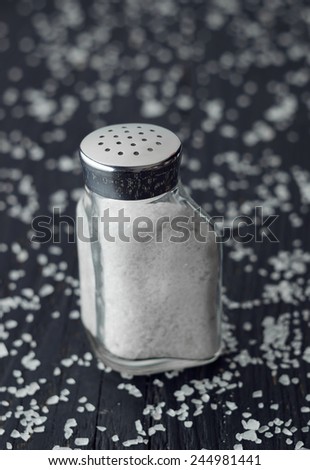 Close up of salt shaker over black wooden table all over it