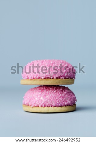 Marshmallow biscuits with pink sugar sprinkles over blue background