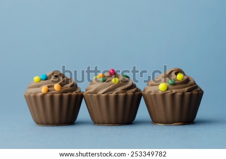 Three Chocolate Cup Cake over blue background
