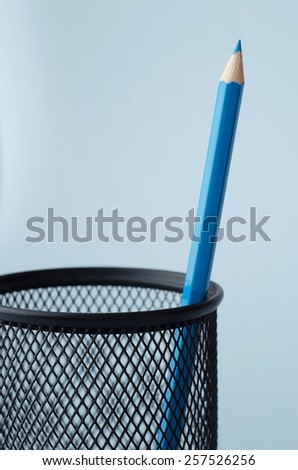 Wooden colored crayon in a pencil box holder over blue background