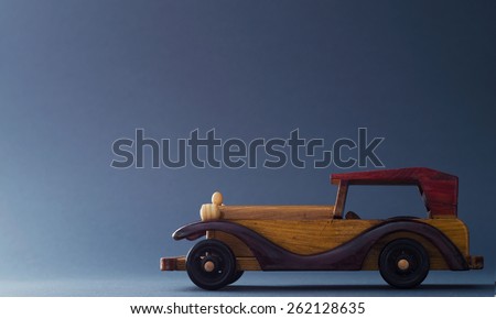 Vintage wooden toy car over dark blue background, image with negative space or copy space.