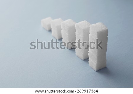 Concept: Ascending stacks of sugar cubes over blue background. This in a concept for high risk of diabetes or other diseases caused by excessive consumption of sugar