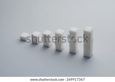 Concept: Ascending stacks of sugar cubes over blue background. This in a concept for high risk of diabetes or other diseases caused by excessive consumption of sugar
