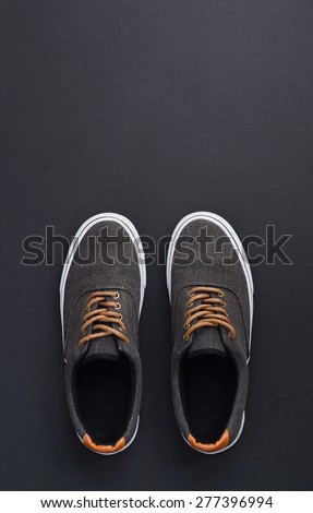 Classic sneakers over dark black background, above view. Image with space for text or other design