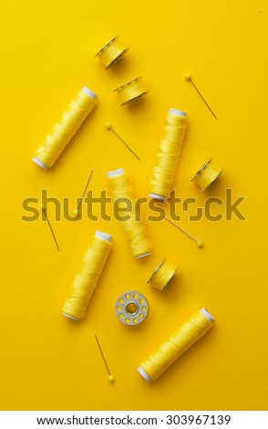 Colorful yellow thread spools over bright yellow background, above view