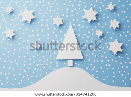 Paper christmas tree, stars and paper snow cut from white paper over blue background, top view