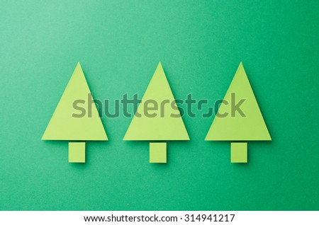 Three Paper Christmas Trees cut from green paper over green background, top view