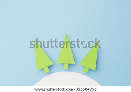 Small Paper Christmas Trees cut from green paper over blue background