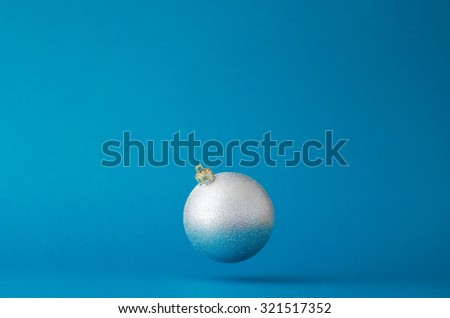 Silver christmas ball floating in the air over blue background with copy space