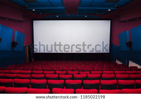 cinema interior of movie theatre with empty red and black seats with copyspace on the screen