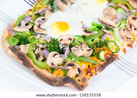 Fresh, healthy, hot baked flatbread vegetarian pizza with 2 eggs sunny side up.