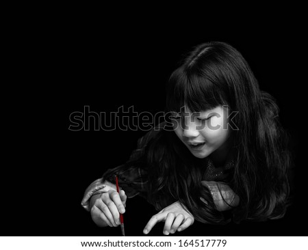 Cute little girl is painting on black background.
