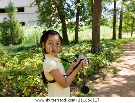 Little girl scout using camera to take pictures on the hiking trail.