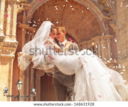 groom carrying bride near church