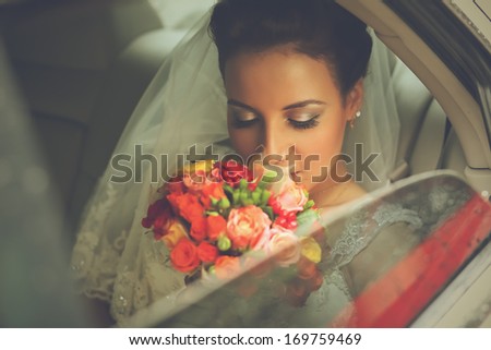bride in veil with bouquet sitting in car
