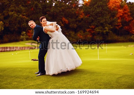 funny happy bride and groom on golf field