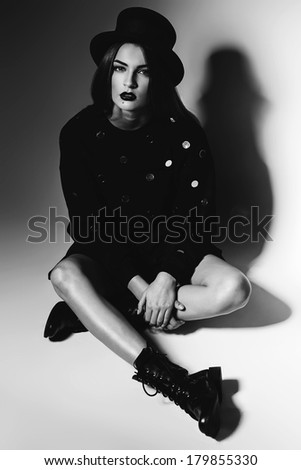 monochrome woman sitting in black hat and boots
