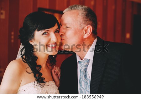father kissing smiling bride