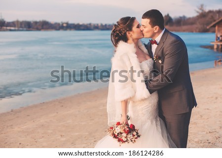 groom and bride kissing on river bank
