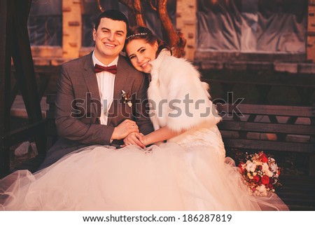 laughing bride and groom on bench at sunset