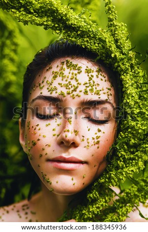 sensual healthy woman holding plant on face