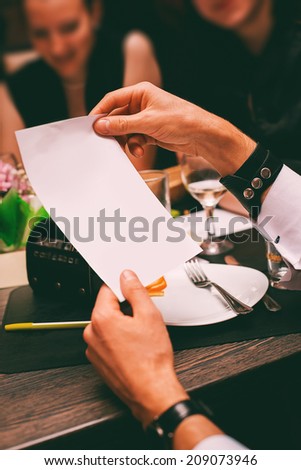 man hands holding sheet of paper in cafe