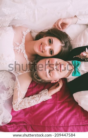 laughing bride and groom lying on bed