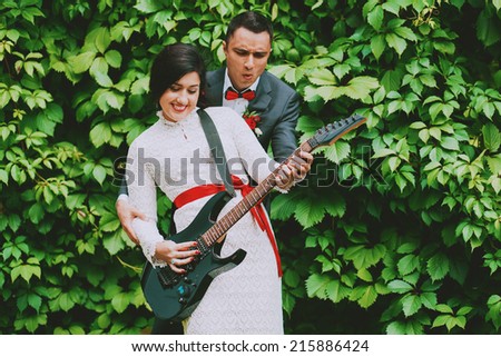 cheerful groom and bride playing the guitar