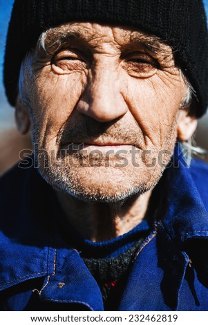 old man in black hat and blue shirt outdoors