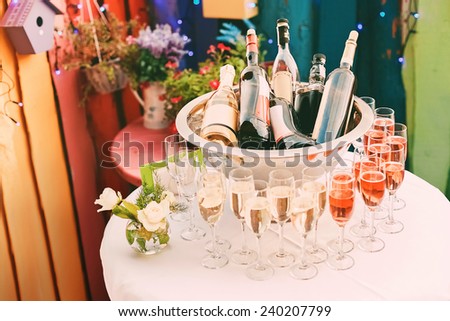 bottles of wine in ice bucket on white table with glass