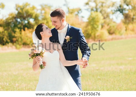 laughing bride and groom on field in sunlight