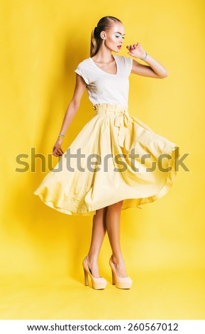 sexy dancing woman in long yellow skirt on yellow background