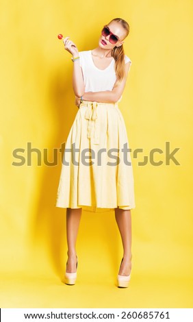 woman in yellow skirt with lollipop on yellow background