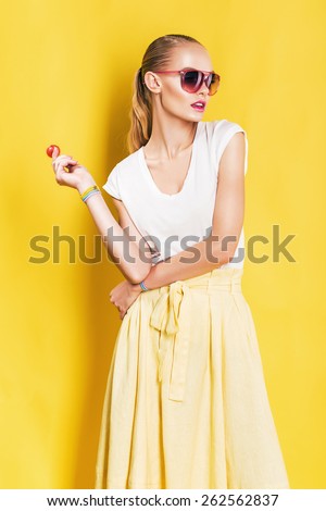 hot woman in long yellow skirt with lollipop on yellow background
