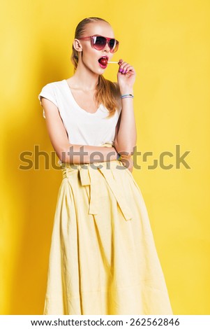 hot woman in long yellow skirt with red lollipop on yellow background