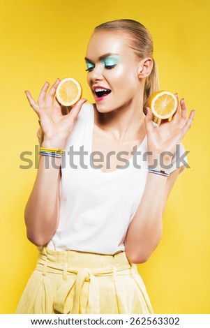 happy woman with lemons in hands on yellow background