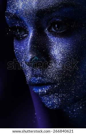 closeup portrait of woman with big eyes in paint in dark