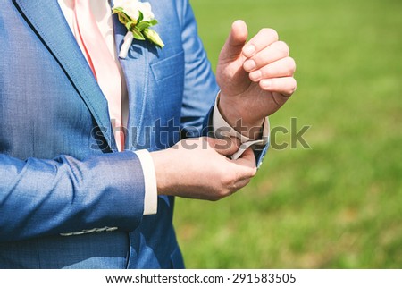 close up portrait of groom in blue suit and pink tie on nature