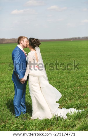 kissing married couple on green field at sunny day