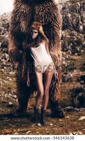 sexy woman with fur hood on head with bear on nature