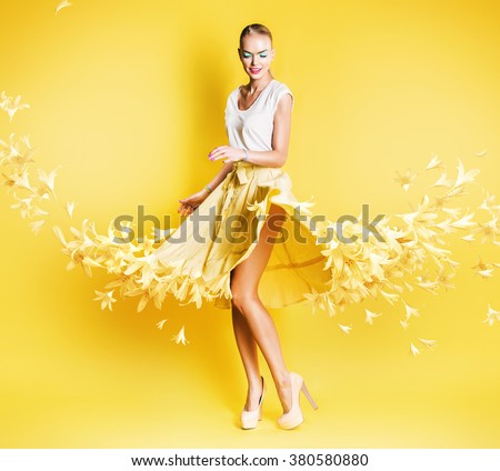 sexy dancing blond woman in yellow skirt of flowers on yellow background